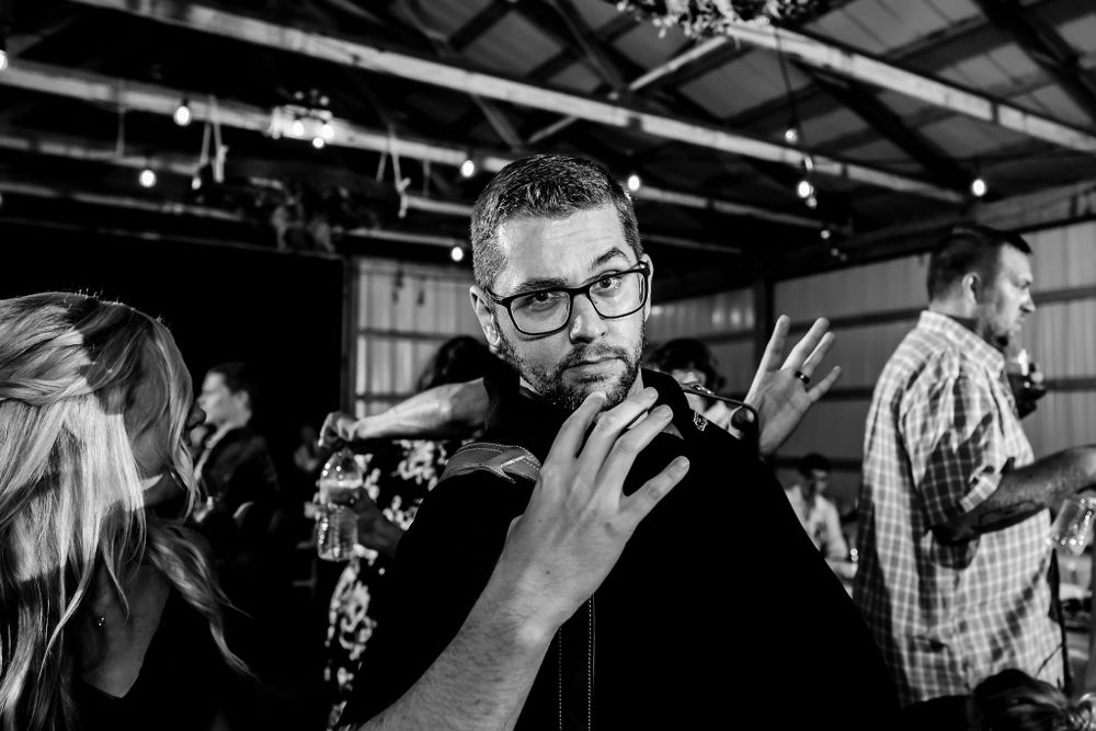 Wedding photographers capture candid moments during a reception in a rustic venue.