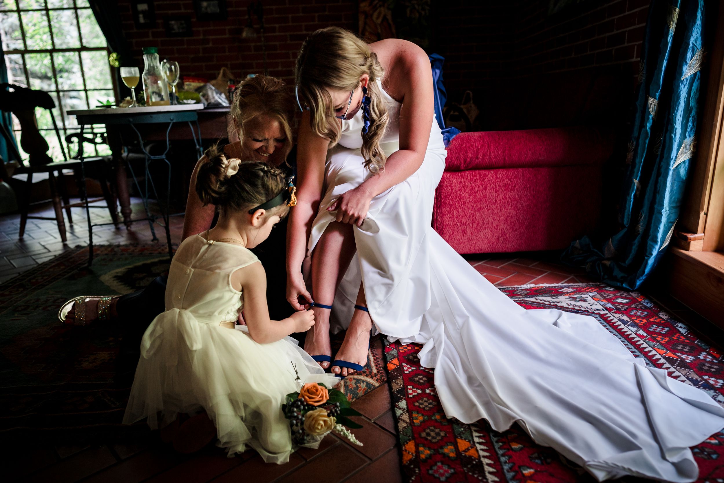 Wedding couple poses on vintage furniture in rustic indoor setting with natural window light.