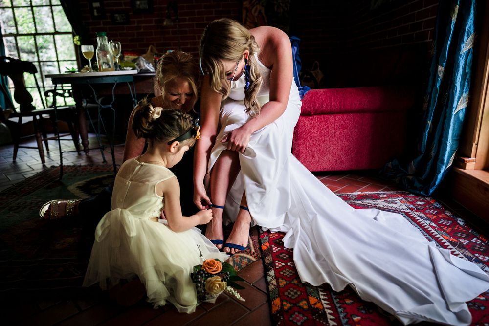 Wedding couple poses on vintage furniture in rustic indoor setting with natural window light.