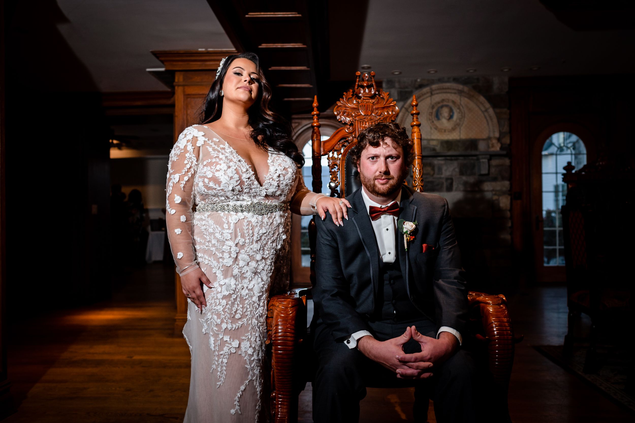 Couple shares intimate moment in dimly lit venue with ornate throne chair.