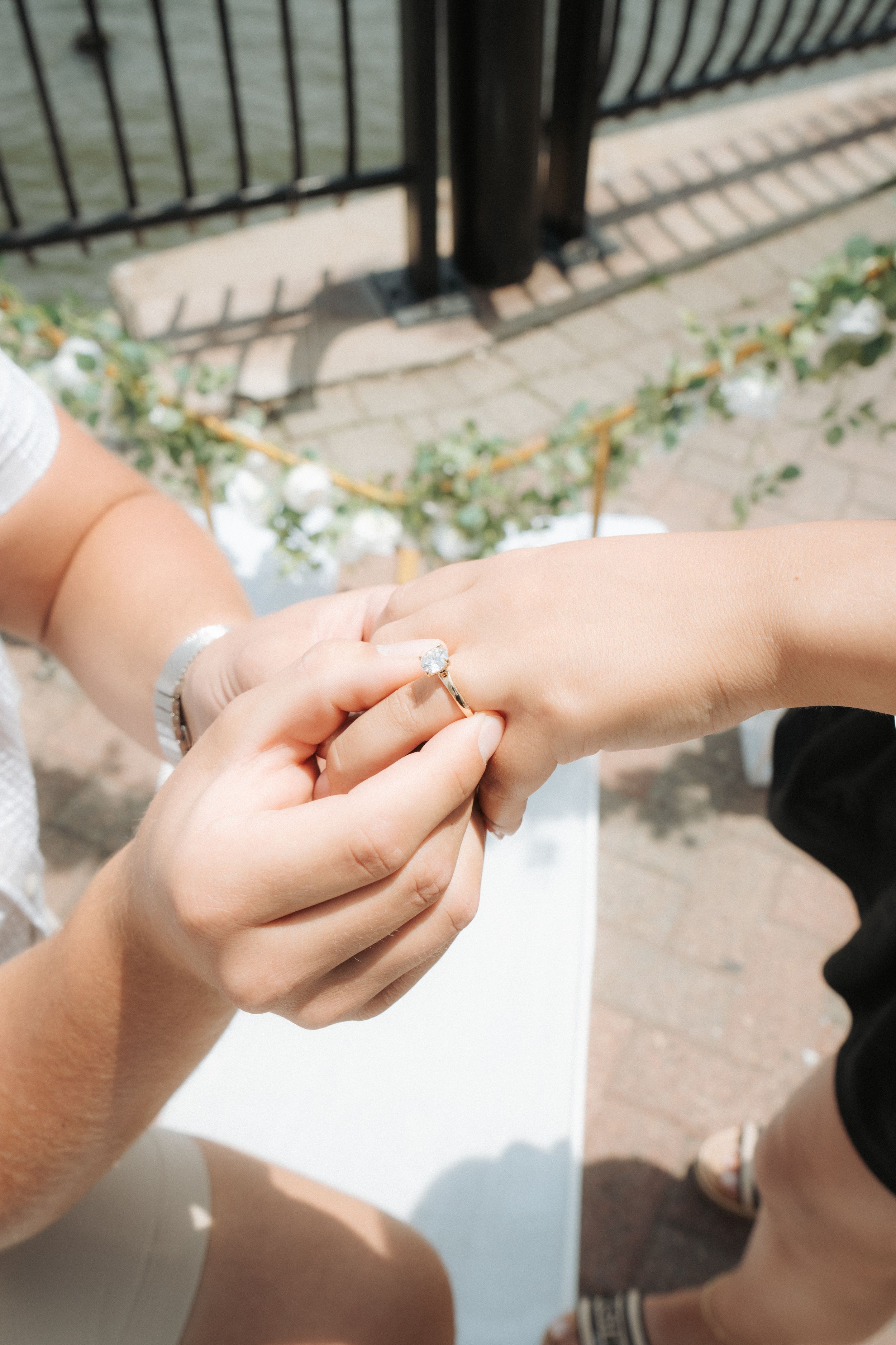Two hands reach toward each other in sunlight showing tender moments of a couple wearing wedding rings.