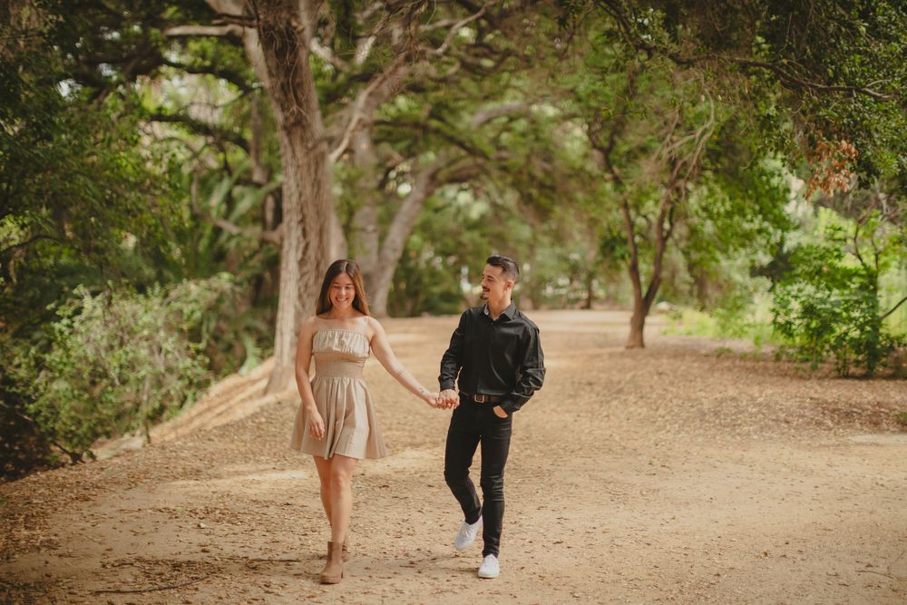 Couple walking together on a scenic outdoor path surrounded by greenery.