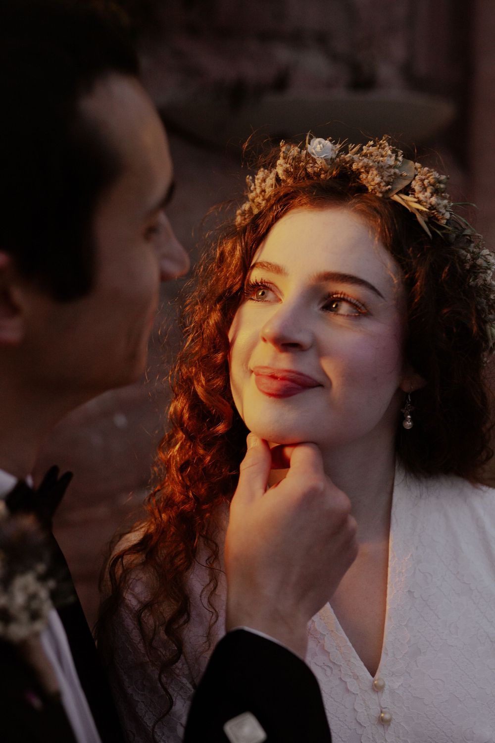 A romantic candlelit wedding portrait shows tender affection between newlyweds.