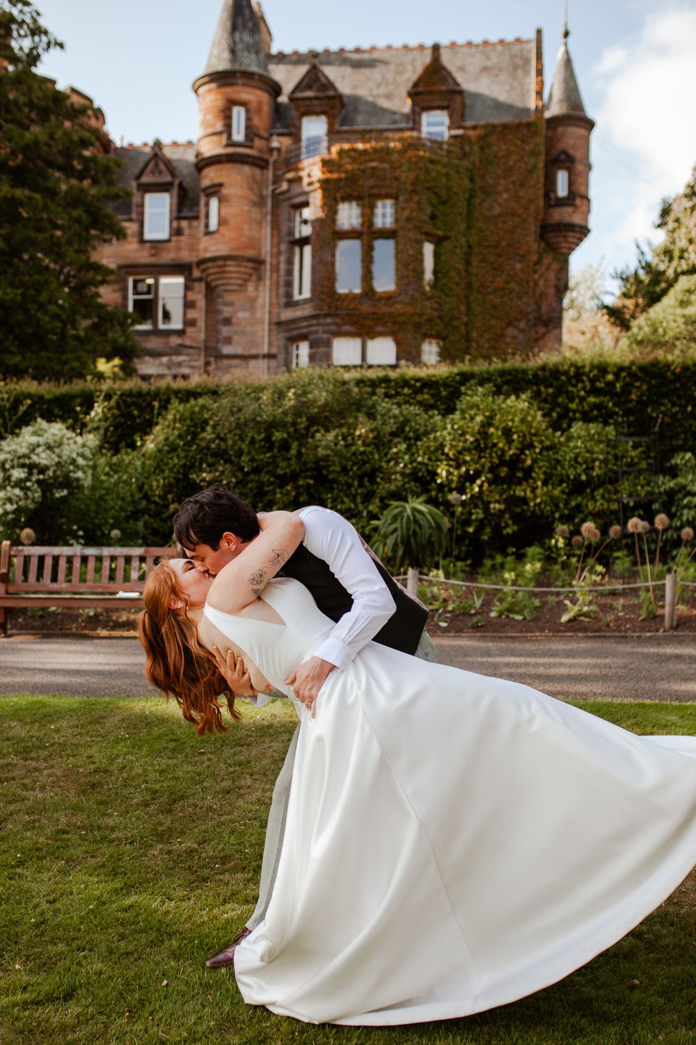 A romantic dip pose with a flowing white wedding dress in front of a stone castle building.