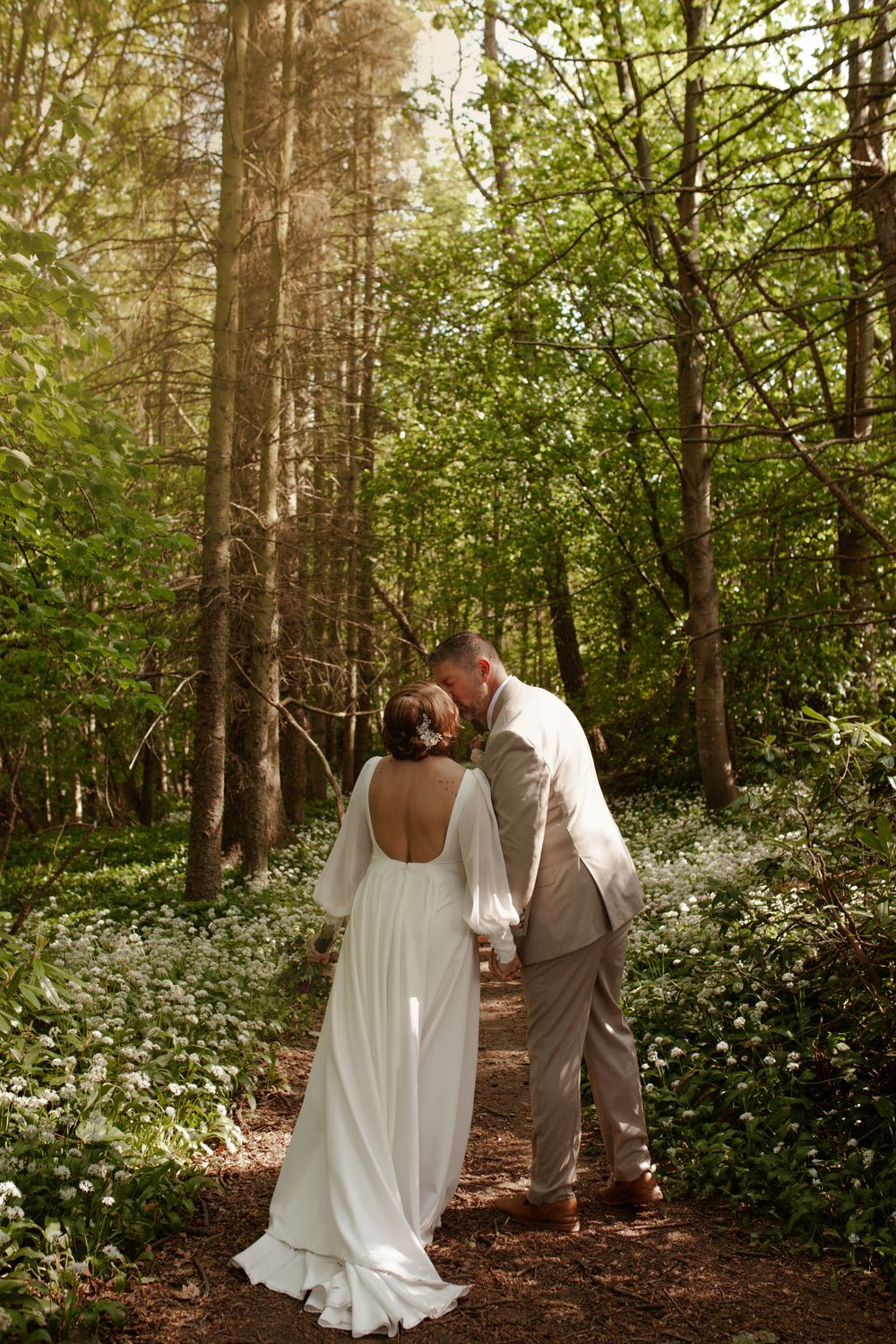 A romantic woodland wedding scene with blooming white flowers along a forest path.