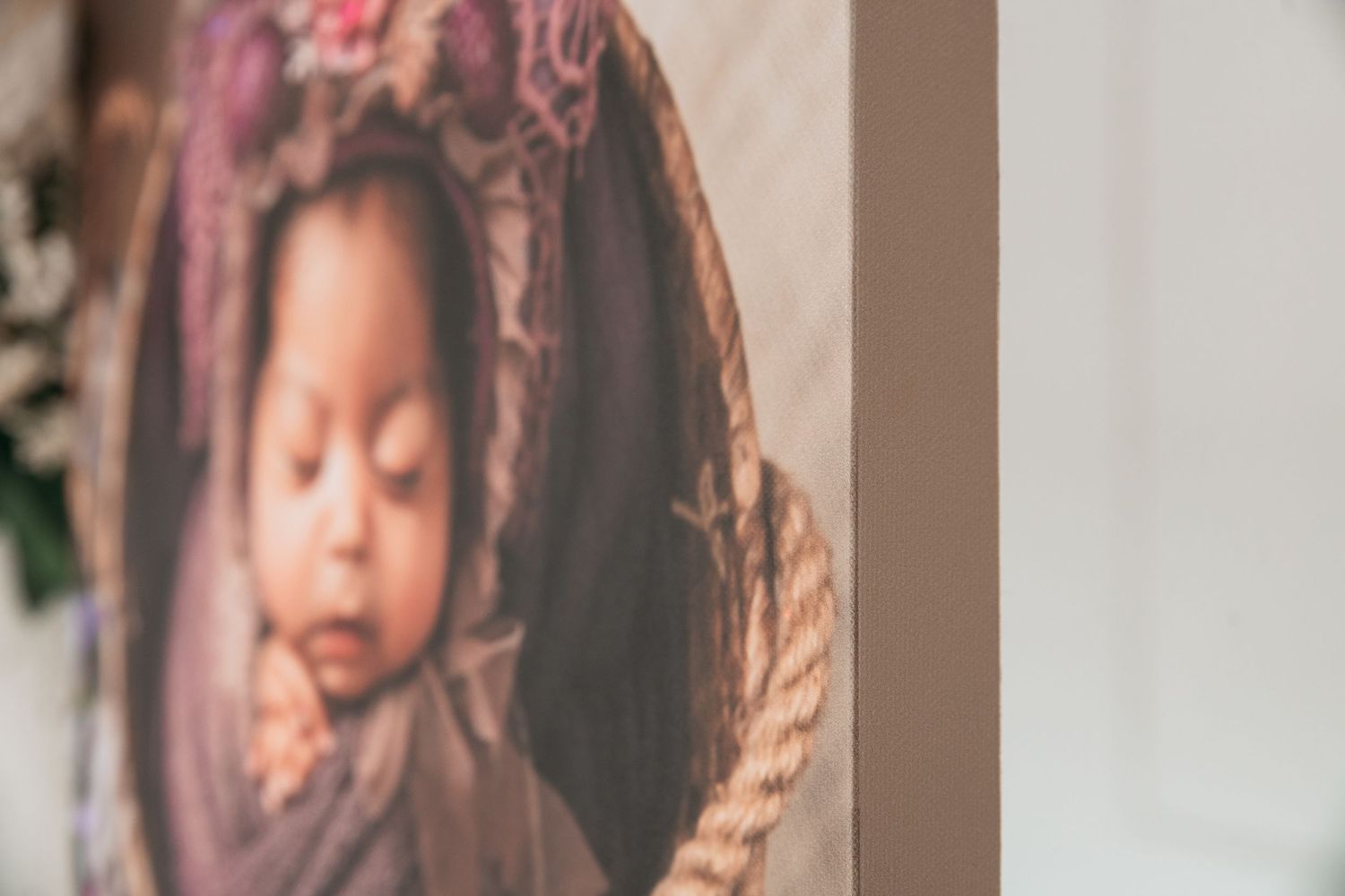 Series of professional newborn photographs displayed on a light colored wall with matching frames.