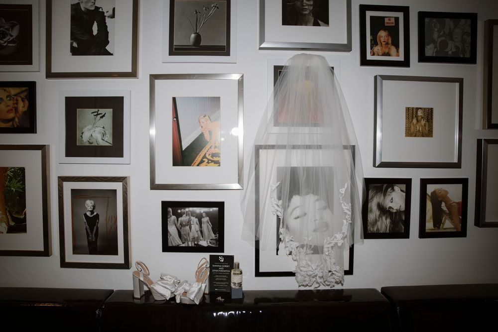 A wall gallery of vintage-style black and white framed photographs with a white wedding veil displayed in the center.
