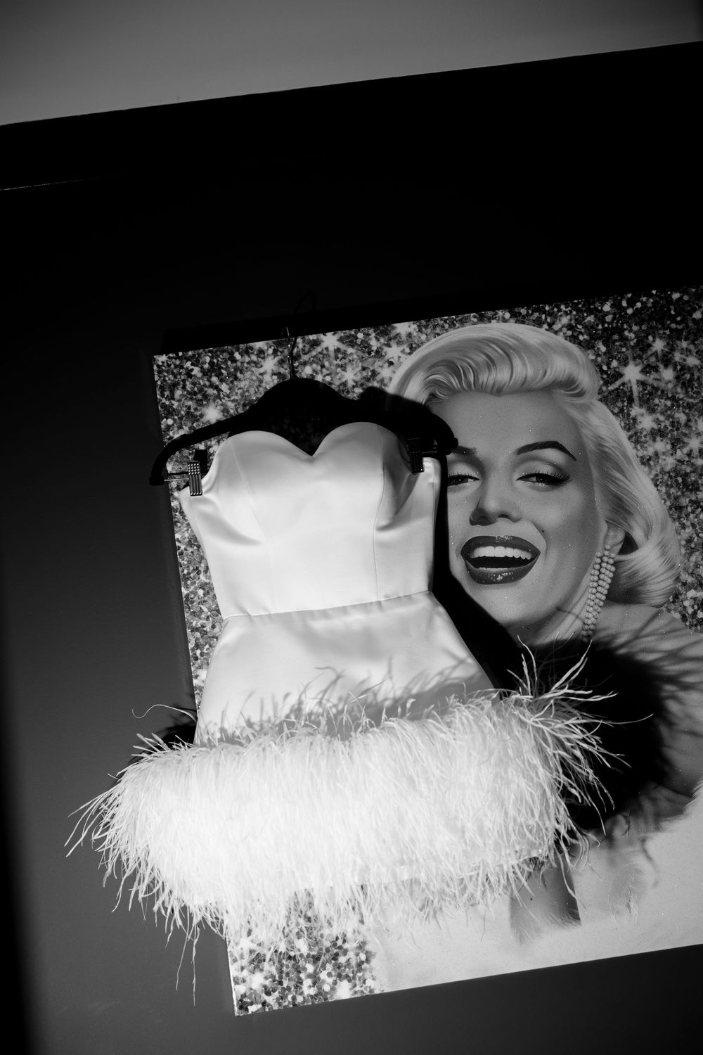 Black and white glamour photo featuring a white feather-trimmed dress and vintage styling.