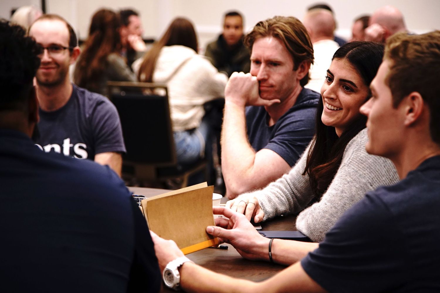 People gathered around tables having animated conversations during a business meeting.