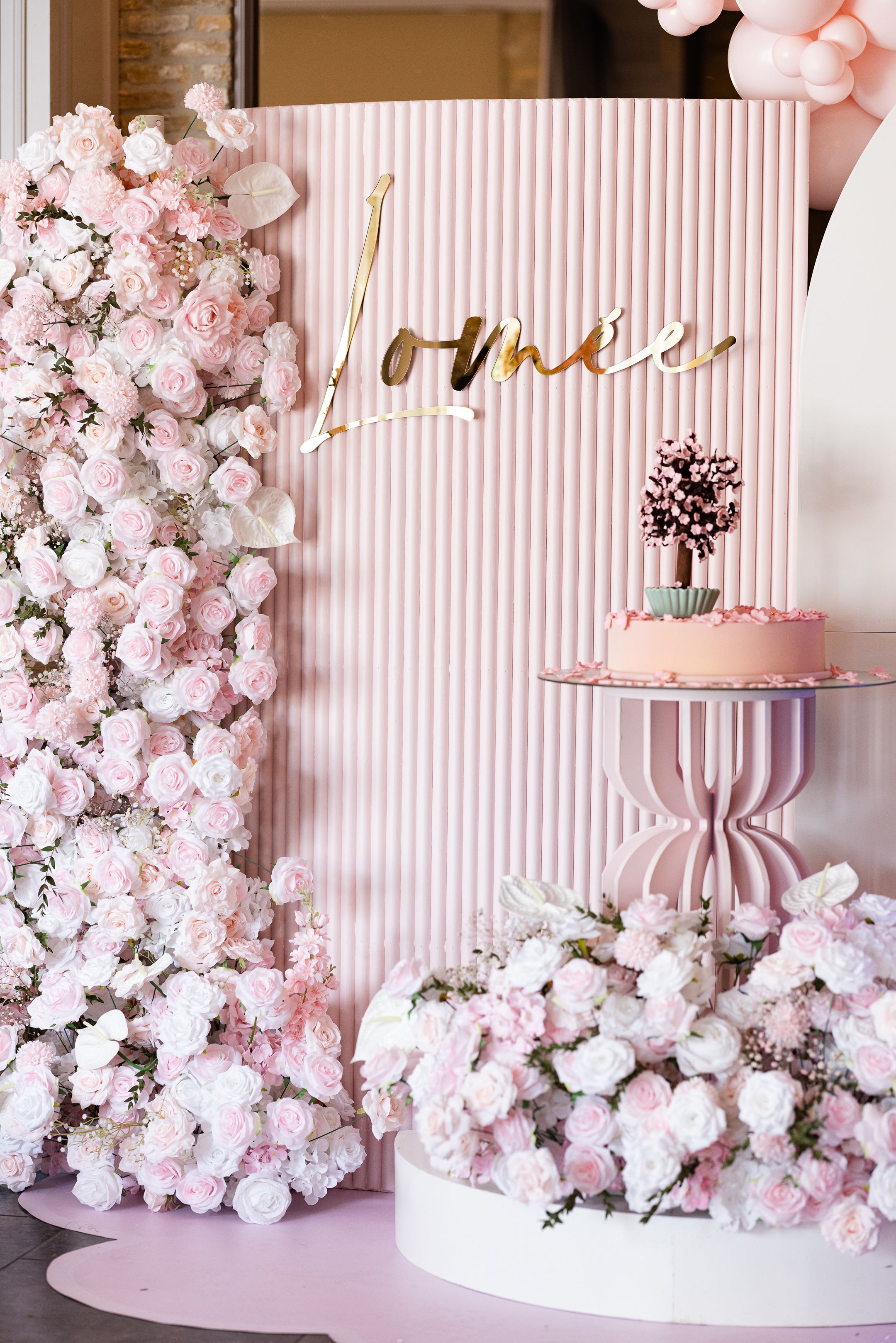 Pink and white floral backdrop with striped pattern and elegant cake display.