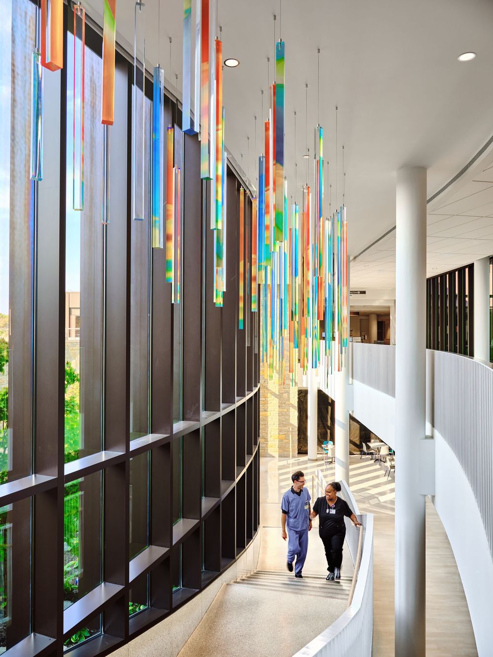 Modern interior hallway with colorful vertical glass panels and natural lighting creating a vibrant corridor space.