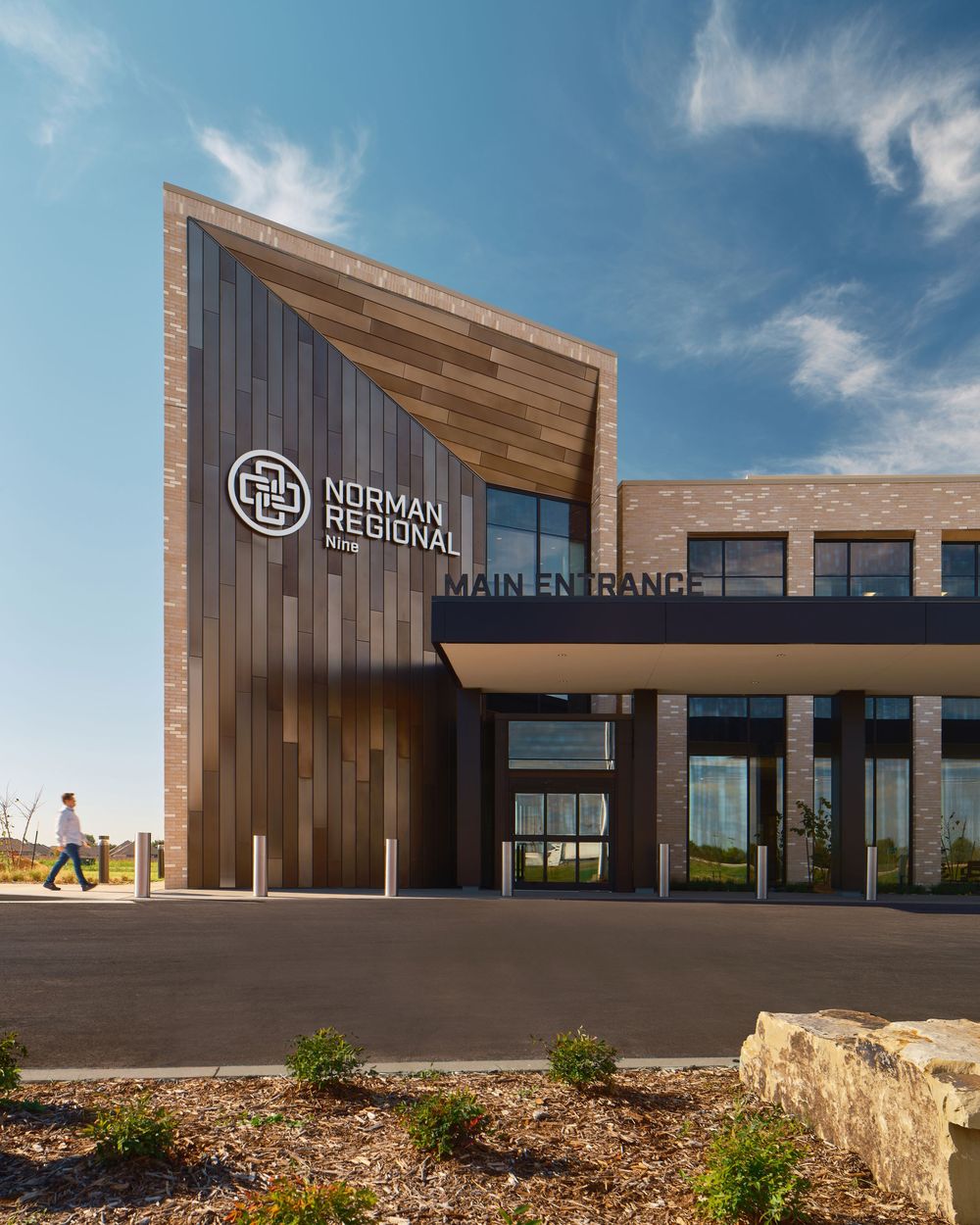 Modern medical facility exterior with wood paneling and glass entrance featuring Normal Regional signage under blue sky.