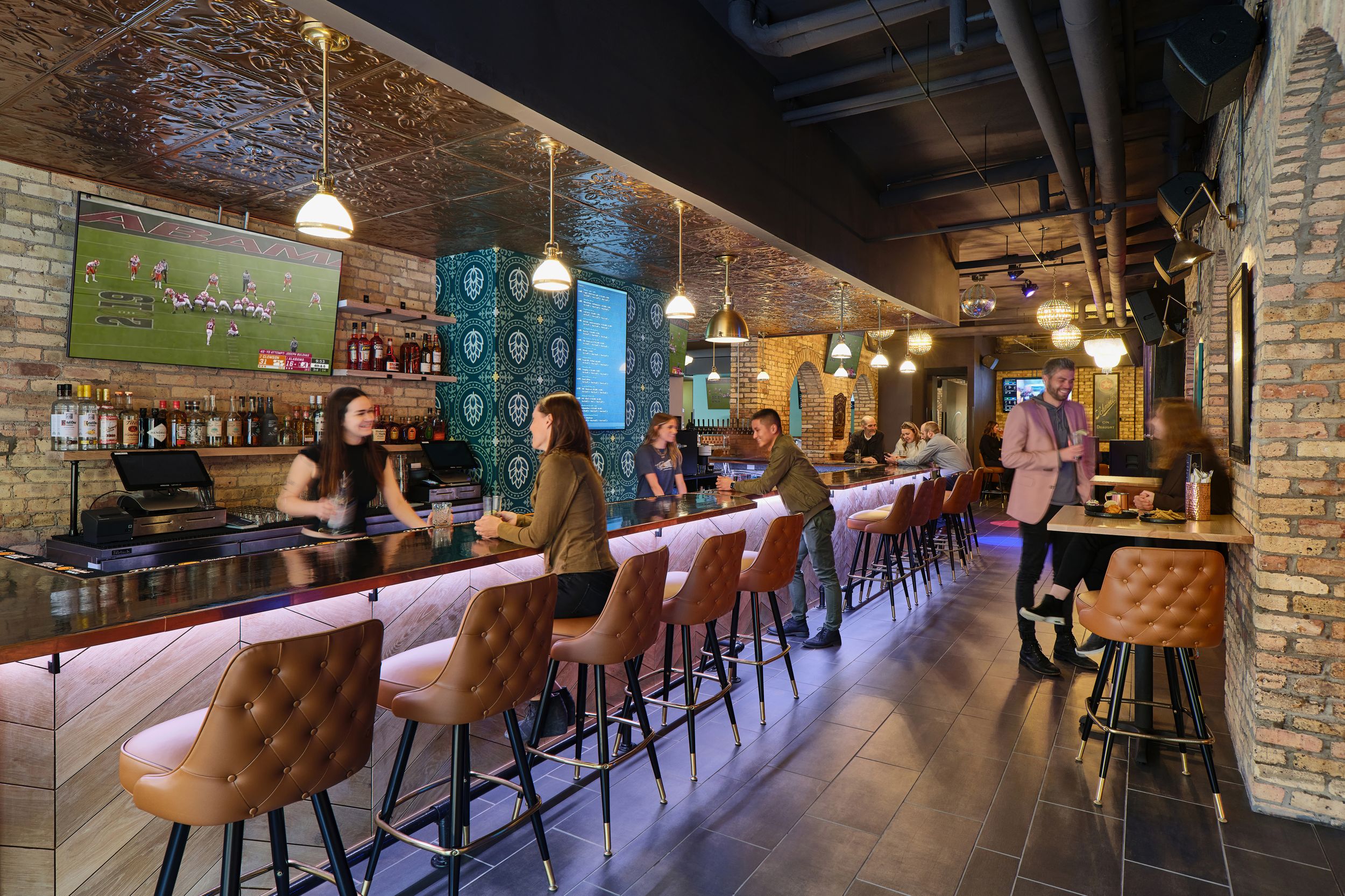 Modern industrial style bar interior with exposed brick walls, wooden bar stools, and pendant lighting creates cozy ambiance.