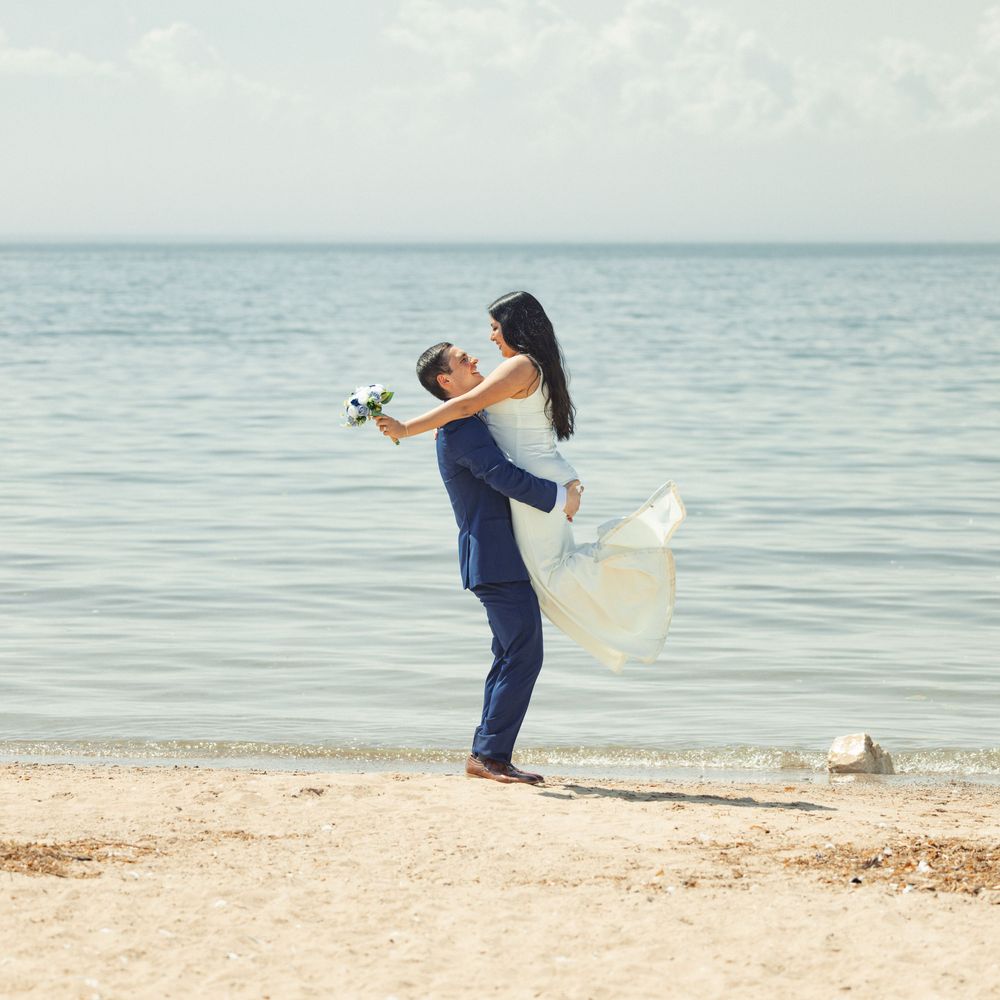 Person in jeans performs dramatic sequence skipping rocks into calm ocean with artistic motion along sandy beach.