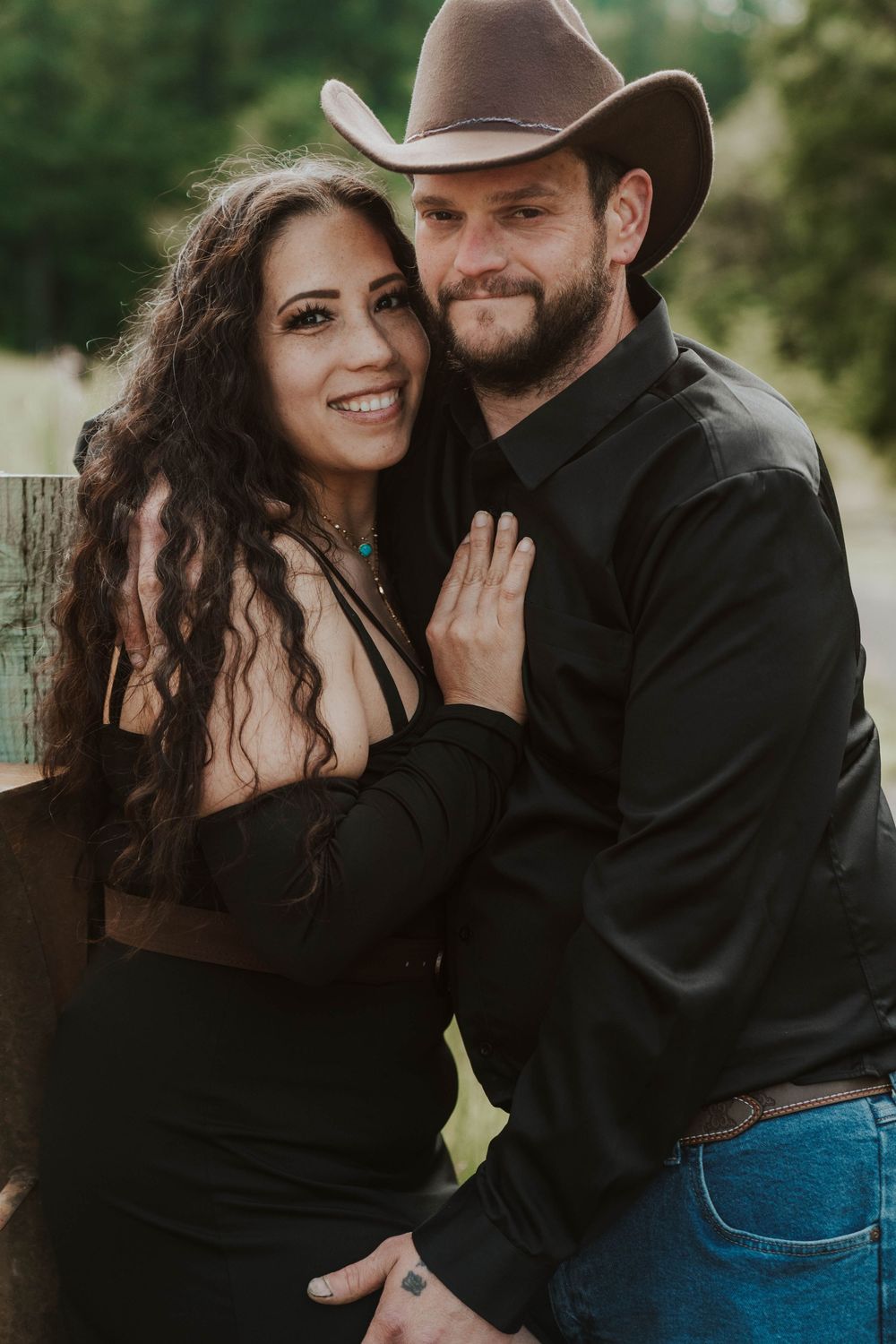 Smiling couple posing together outdoors, man wearing a brown cowboy hat.