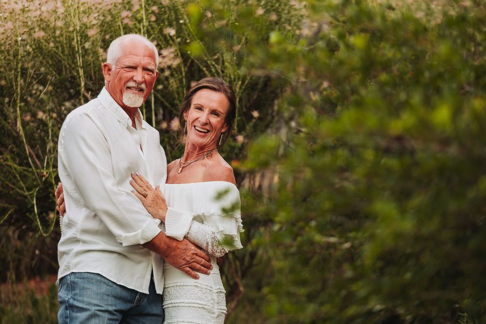 An intimate outdoor photoshoot showing a couple dancing and embracing in a garden setting with golden sunlight.