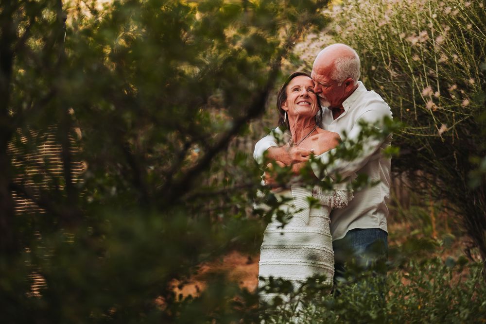 A loving couple embraces in a dreamy garden setting during golden hour as sunlight filters through foliage.