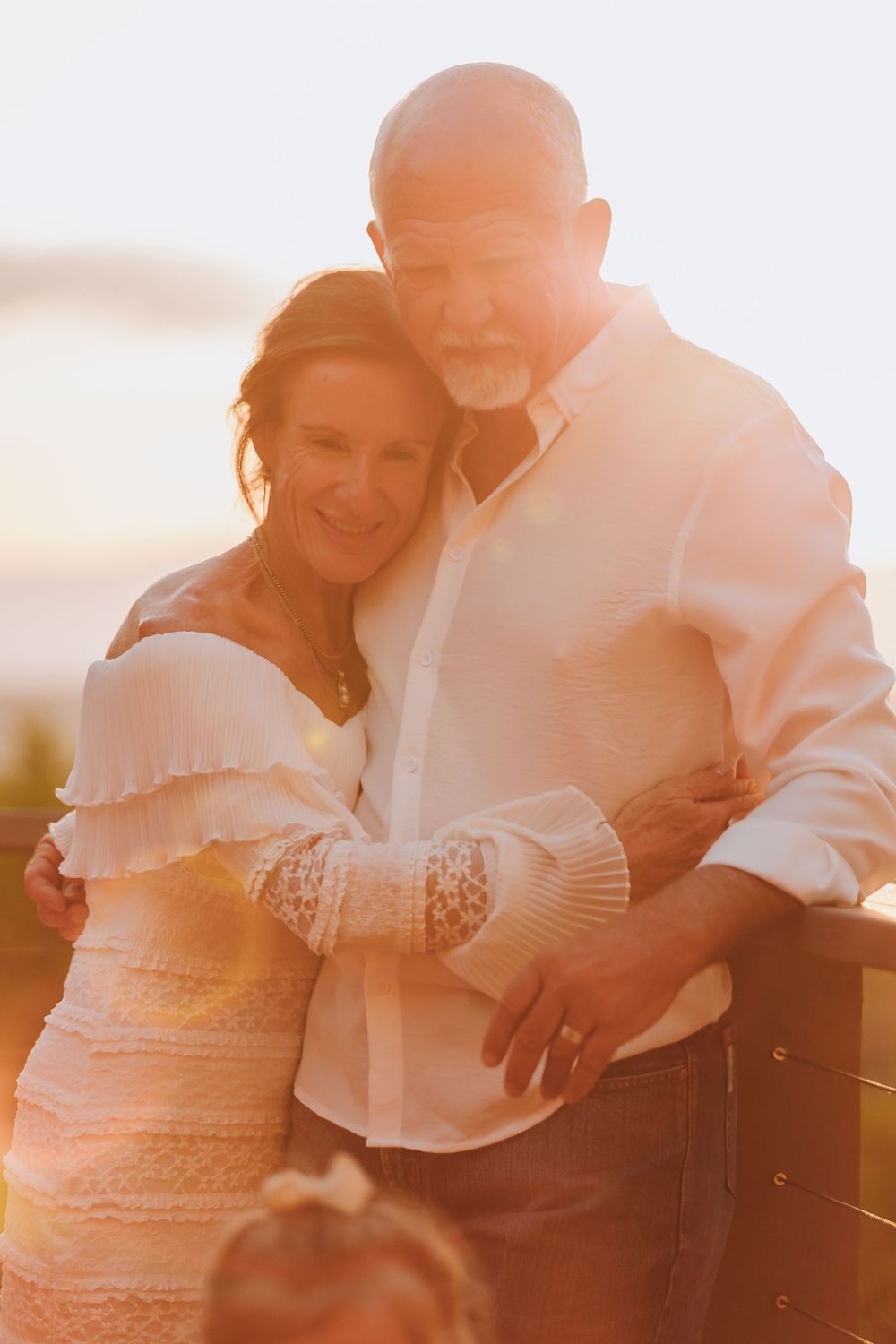 A couple embraces lovingly during an outdoor photo shoot at golden hour.