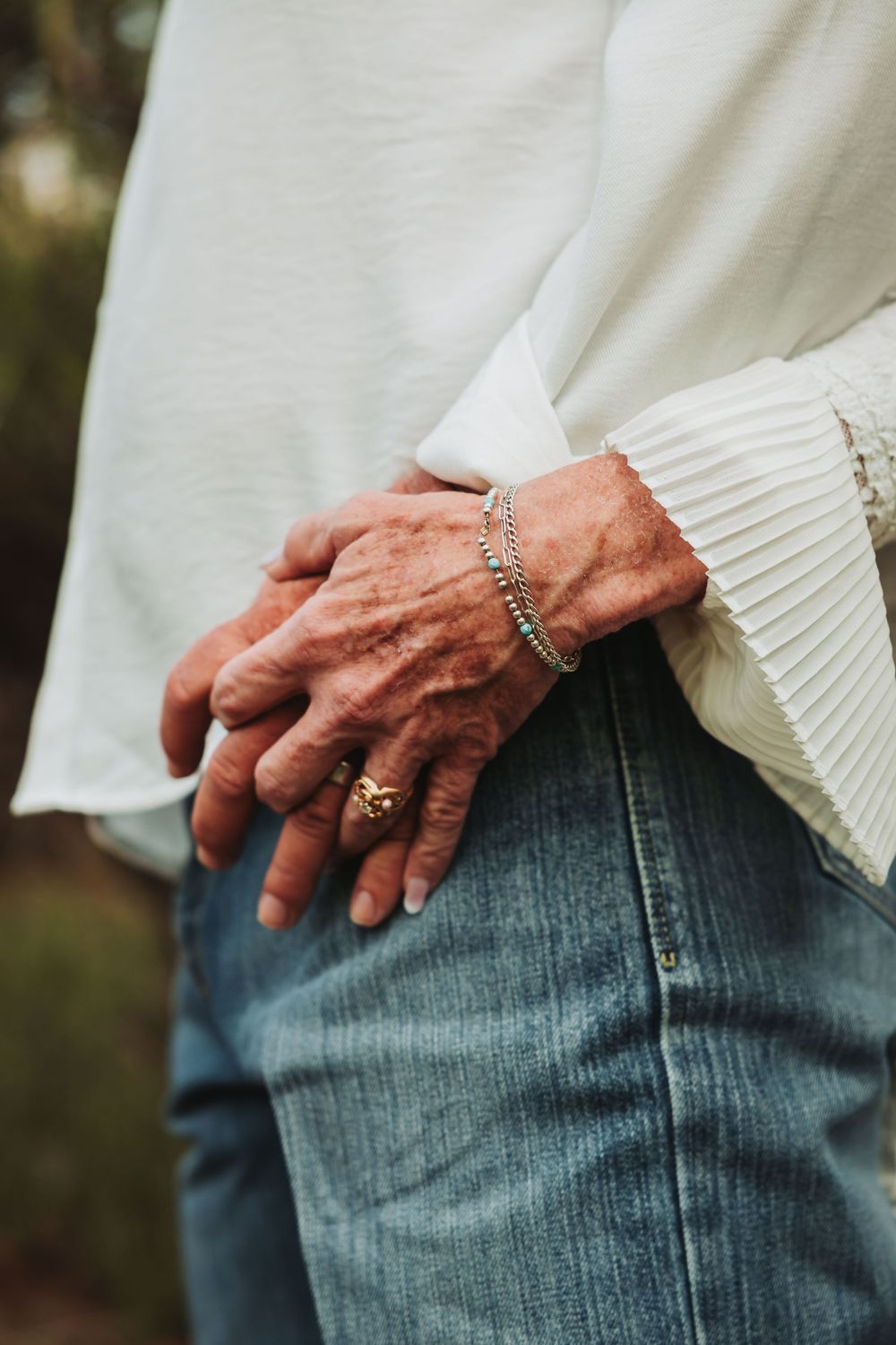 A close-up sequence showing a hand with rings resting against blue denim jeans and white sweater material.