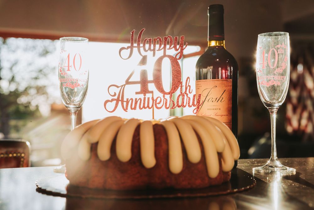 Four celebratory cake images with wine glasses and anniversary decorations displayed in soft lighting at a party.