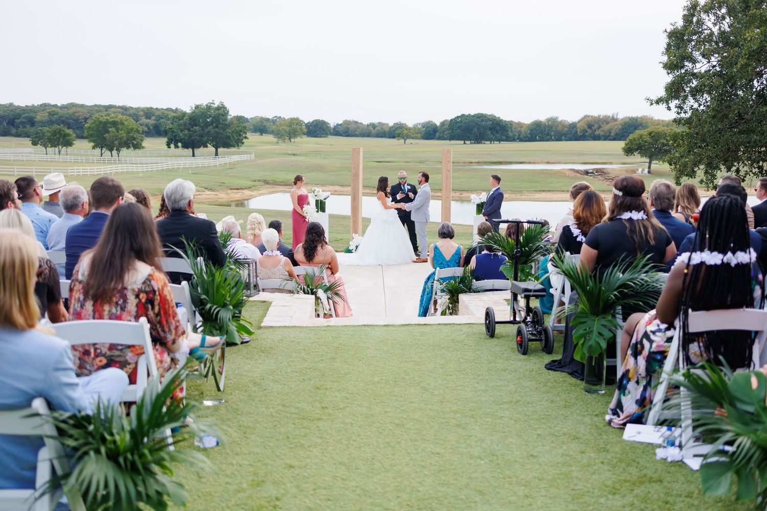 Rows of folding chairs on a grassy lawn at Bella Cavalli create an outdoor event setup with guests seated in the background.