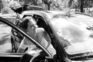Black and white portrait of bride looking out car window on wedding day.