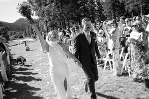 Black and white photo of a joyful bride and groom walking down the aisle after their outdoor wedding ceremony.