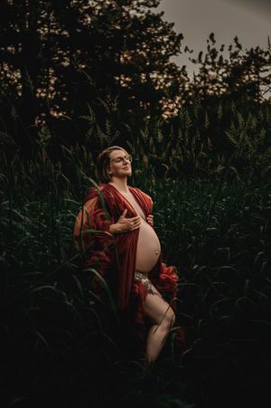 A figure in red lounges in a cornfield under dark moody lighting at sunset.