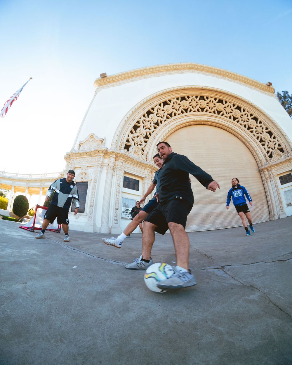 A man dribbles a soccer ball in front of the grandstand in Balboa Park