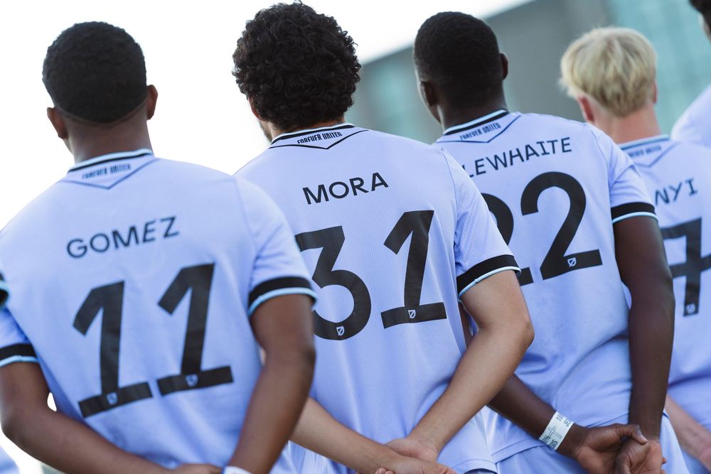 4 people stand shoulder to shoulder with their hands behind their back