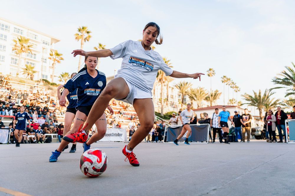 A female soccer player dribbles the ball reaching out for it