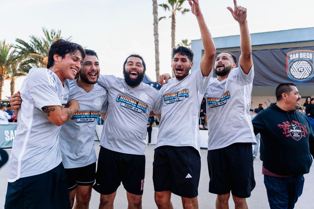 A group of men celebrate with their hands in the air cheering and smiling