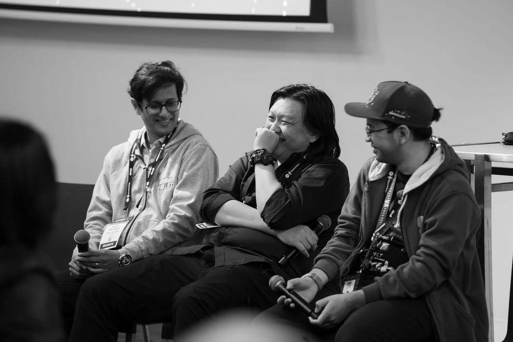 A series of black and white candid photos capturing workshop or meeting participants in discussion settings.