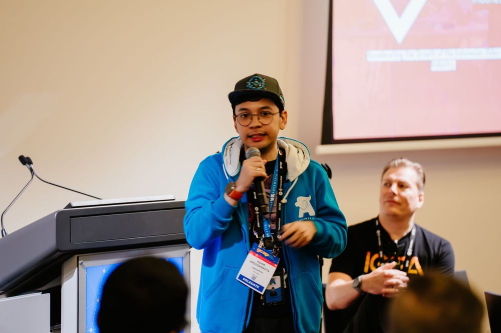 Speaker presenting at a technology conference panel while others listen and engage with the audience.