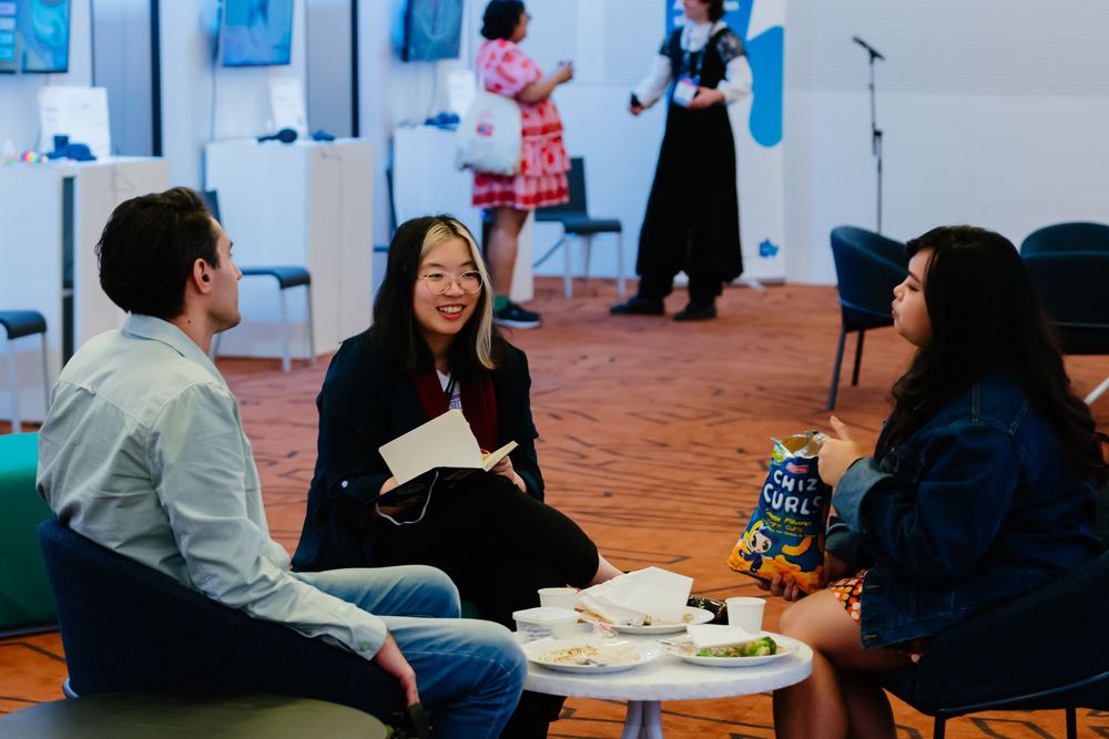A business networking event in a modern venue with people gathered at round tables for conversation and socializing.