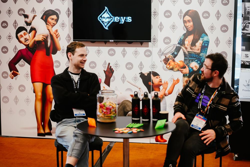 Group of people gathered at a gaming event with monitors and tables visible in a conference room setting.