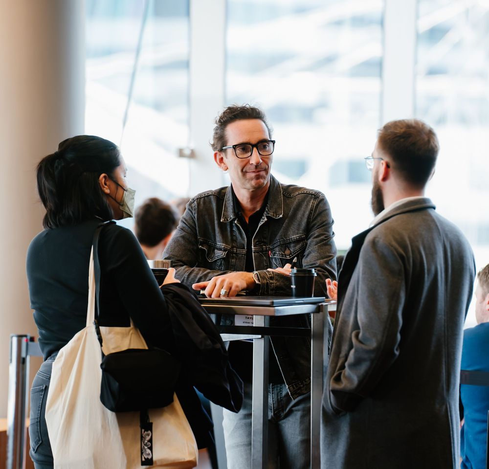 Business professionals gather at a modern office space for a meeting with colleagues over drinks and conversation.