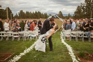 A romantic dip kiss during a wedding recessional with guests cheering on either side of the aisle.