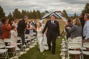 Wedding guests cheer as the couple walks down the aisle during their outdoor ceremony exit.