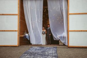 White fabric curtains frame an indoor venue entrance with sparkling lights visible in the background.