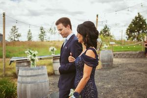 Rustic wedding venue decorated with string lights and wine barrels against cloudy country landscape.