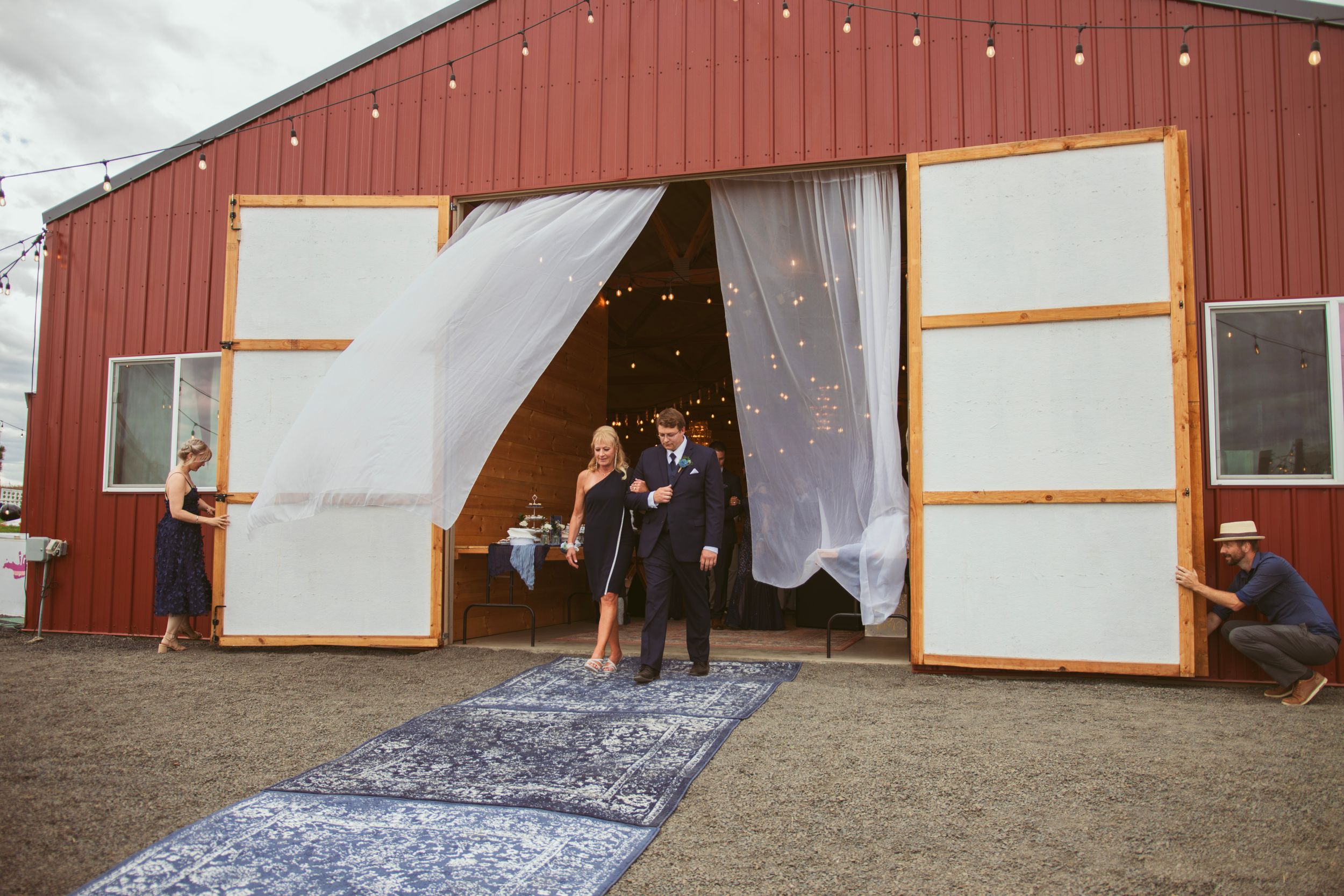 White fabric curtains flutter gracefully in front of a red barn wall with wooden trim details.