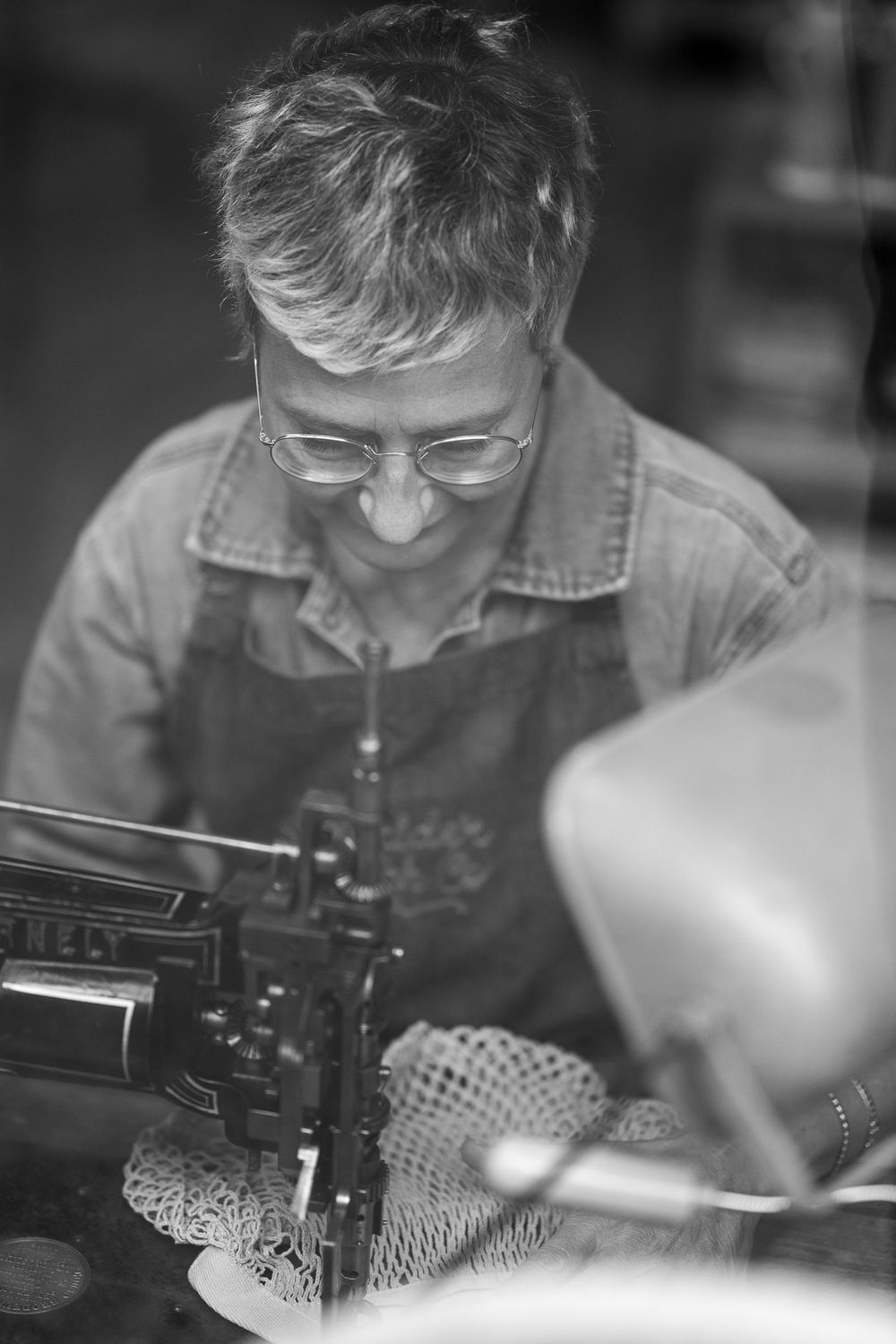 Craftsman focuses on detailed work with a vintage sewing machine in black and white photography.