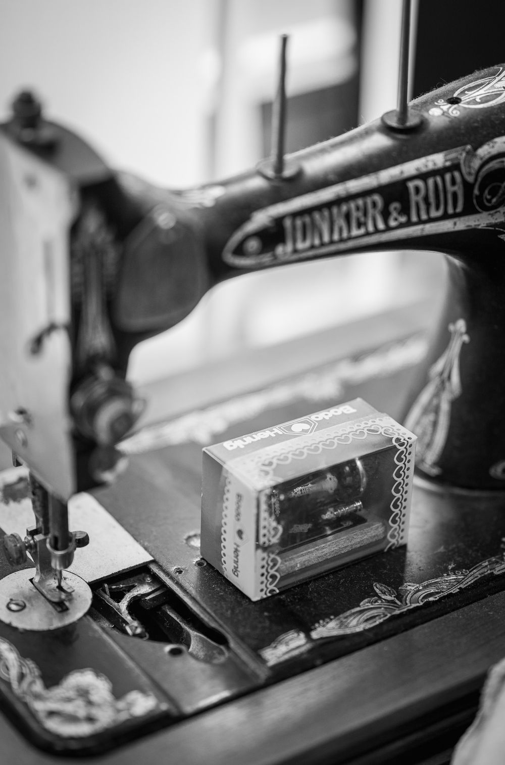 Vintage Junker & Ruh sewing machine shown in black and white with decorative details and small box on its surface.