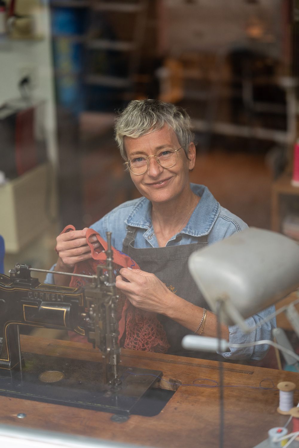 An artisan carefully handles fabric while working at a traditional wooden sewing station.