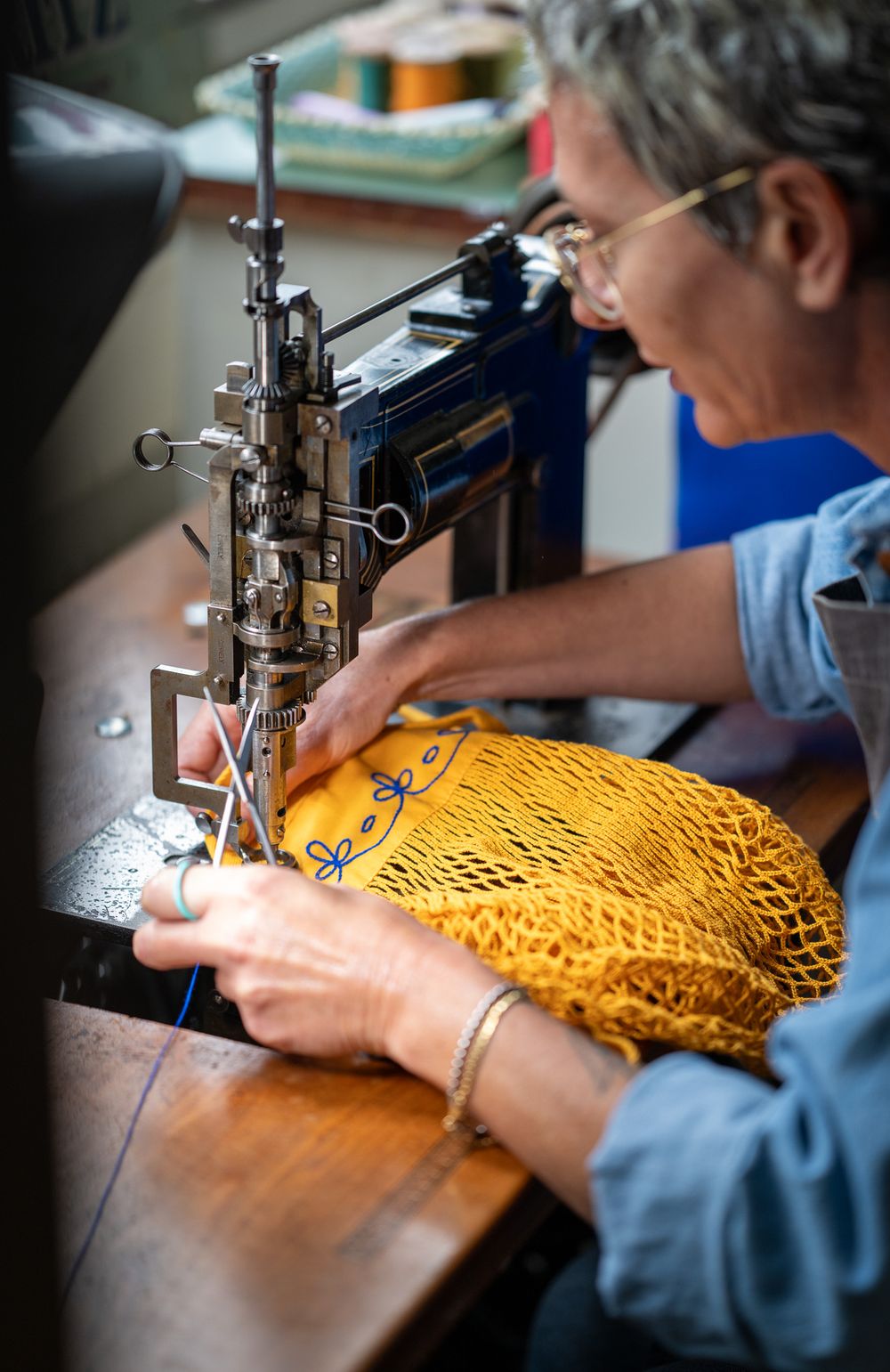 Close-up shots of a person sewing a bright yellow mesh fabric on an industrial sewing machine.