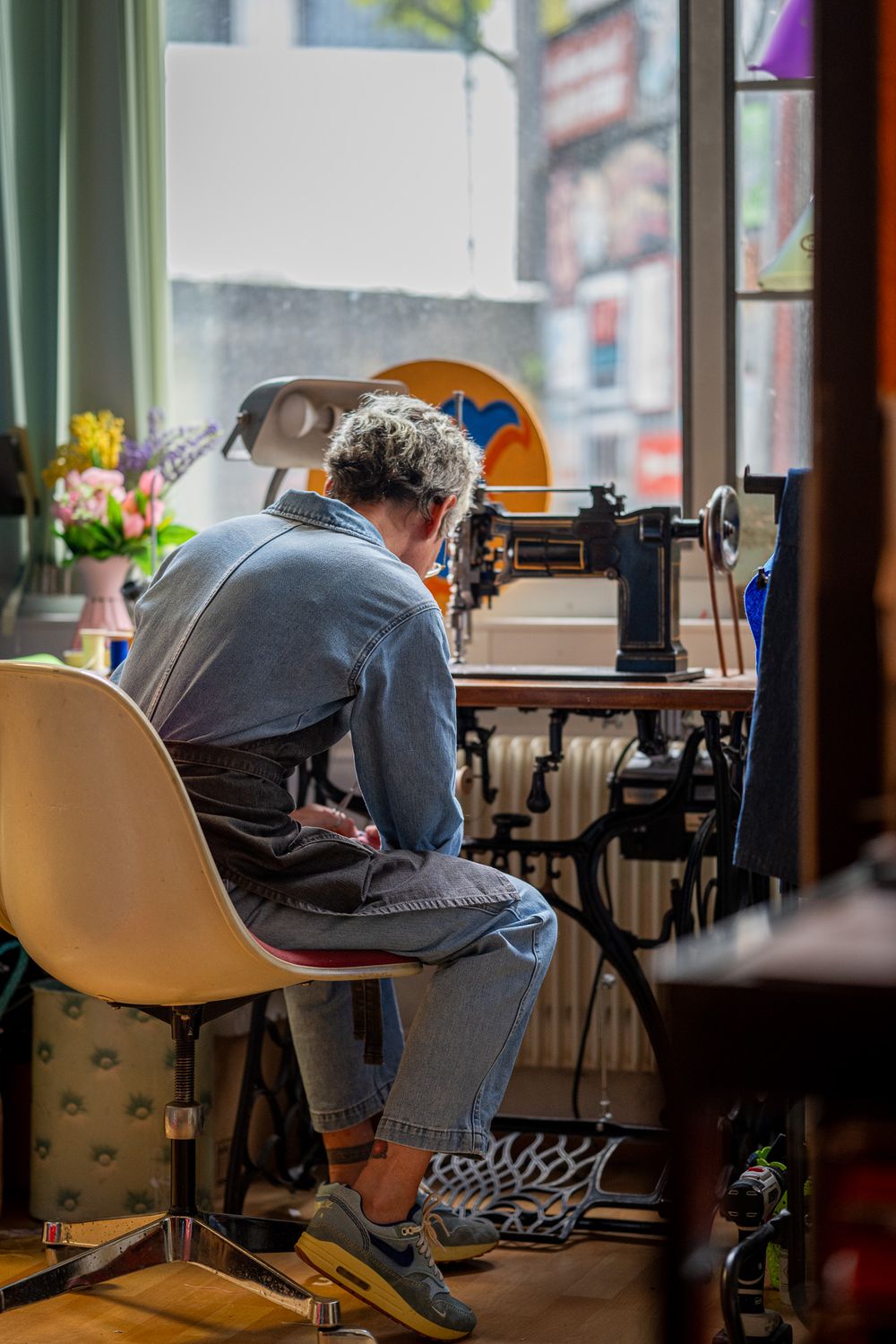 Someone works on a laptop at a cafe counter near windows with natural light streaming in during daytime.