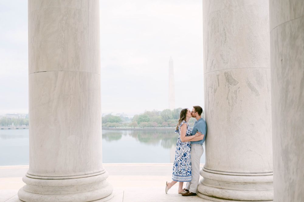A romantic scene framed by white marble columns overlooking water.