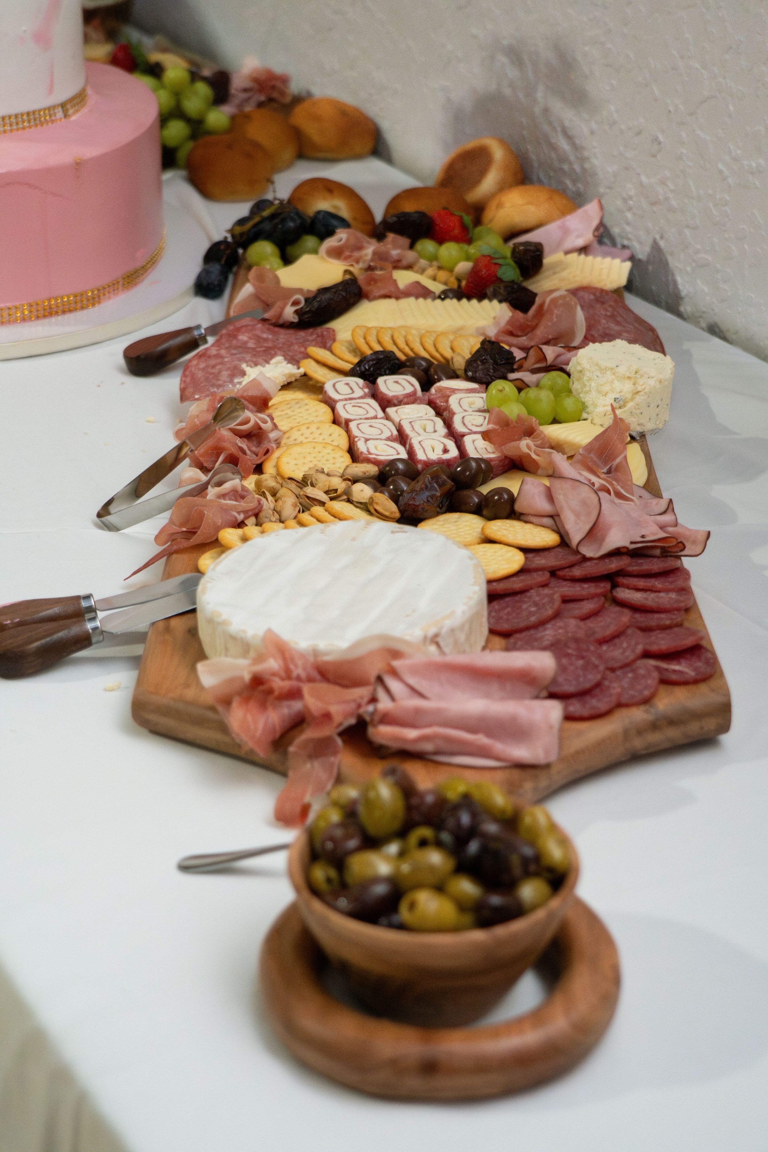 Elegant charcuterie board with meats, cheeses, crackers, and olives displayed at a quinceañera party.