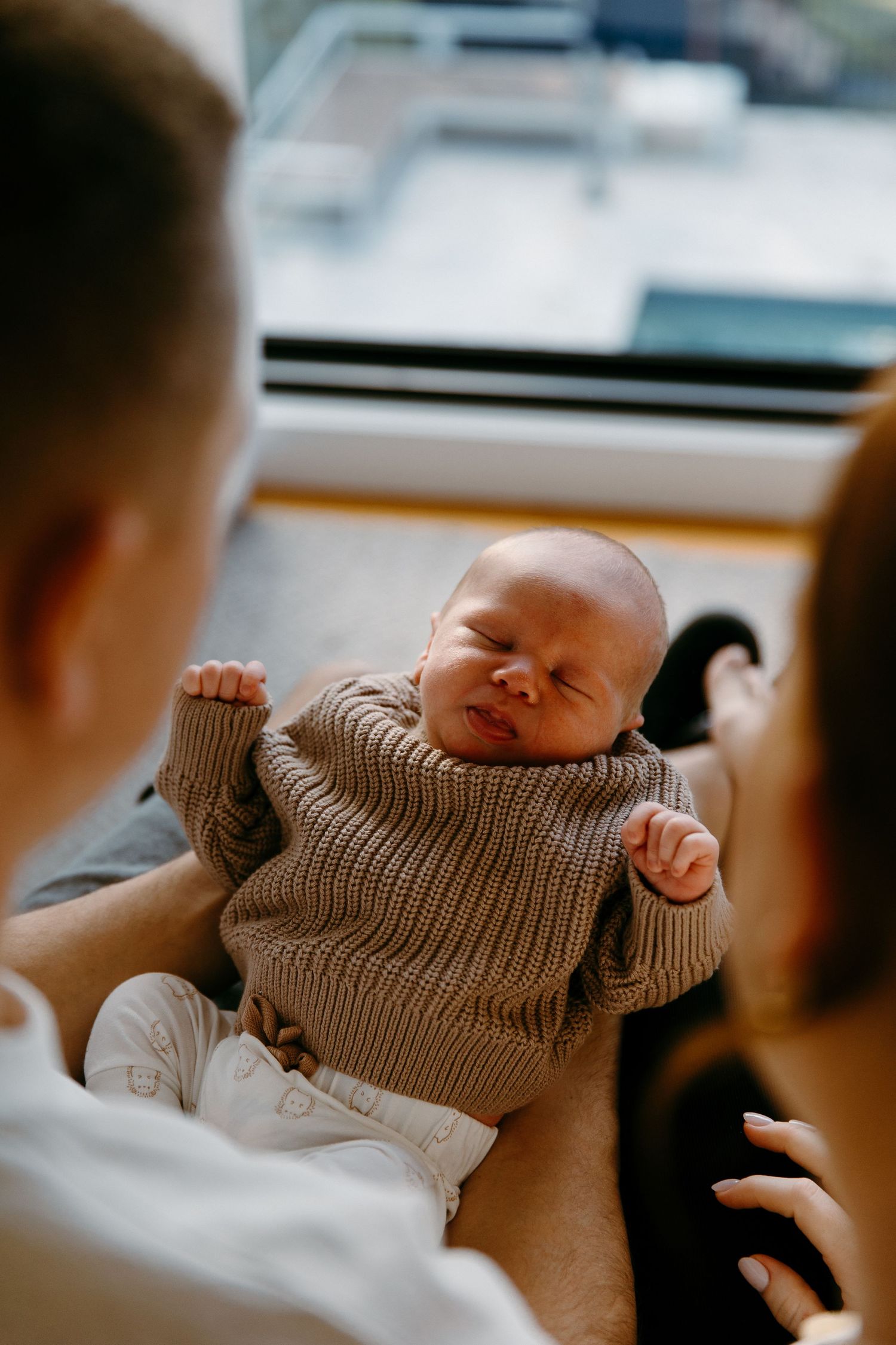 Three photos show a sleeping newborn baby swaddled in a cozy brown knit sweater.